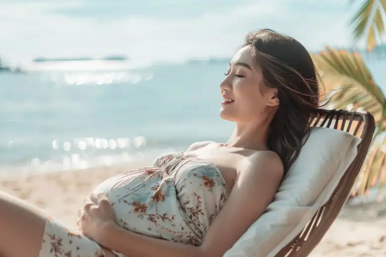 gestante feliz observando o por do sol em uma praia